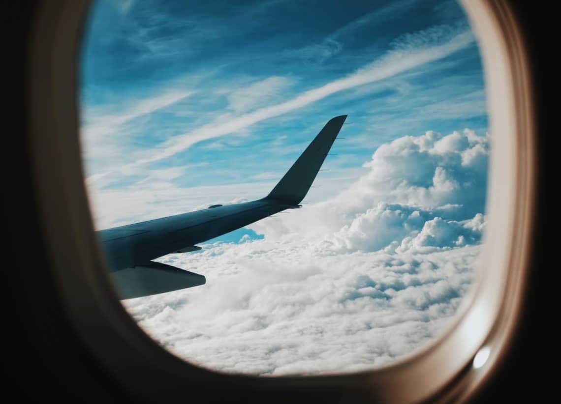 person taking picture of plane wings while flying during daytime