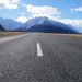 gray asphalt road near mountain range under blue sky during daytime